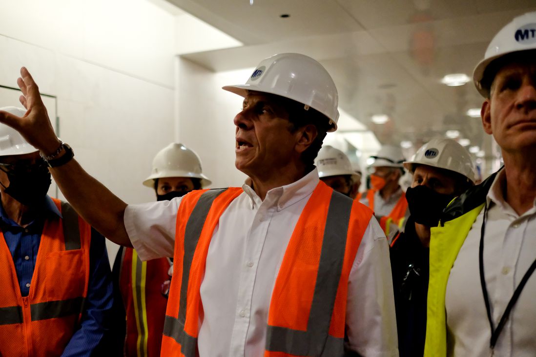 Governor Cuomo, in a hardhat and vest, gestures as he speaks